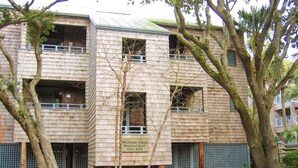 Een meerhoog gebouw met een bord waarop staat dat het een hotel is, genaamd 'Windswept Villas', met telefoonnummer 4332-4335.