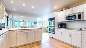 Una cocina moderna con armarios blancos, electrodomésticos de acero inoxidable y suelo de madera.