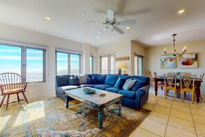 Relax in this spacious living room with a sofa, dining area, and ocean views.