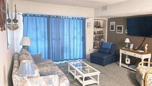 A living room with a sofa, armchair, coffee table, and a bookshelf.