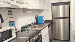 A modern kitchen with a microwave, stove, sink, and stainless steel refrigerator.