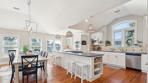 A spacious kitchen with a large island, white cabinetry, and a wooden floor. - Heatable Pool, Short Walk to Beach, Luxury Living! Sweet Carolina (Folly Beach)