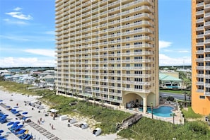 Hotel alto com várias varandas, área de piscina e acesso à praia.