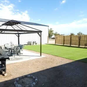 A patio area with a covered seating area, a barbecue grill, and a small fire pit.