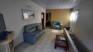 Uma sala de estar com um sofá cinzento, um sofá azul, uma mesa de centro de madeira com revistas e um quadro na parede.