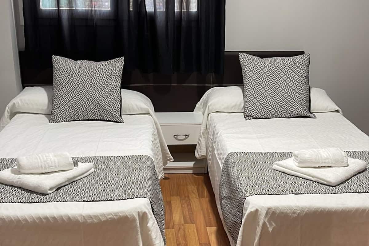 Ein Doppelzimmer mit zwei Betten, jeweils mit gemusterten Kissen und einem weißen Handtuch.