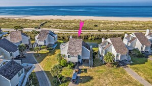 An aerial view of a coastal residential area with houses, a beach, and a clear sky.