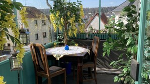 Une terrasse couverte avec une table et des chaises, entourée de plantes en pot et offrant une vue sur la ville.
