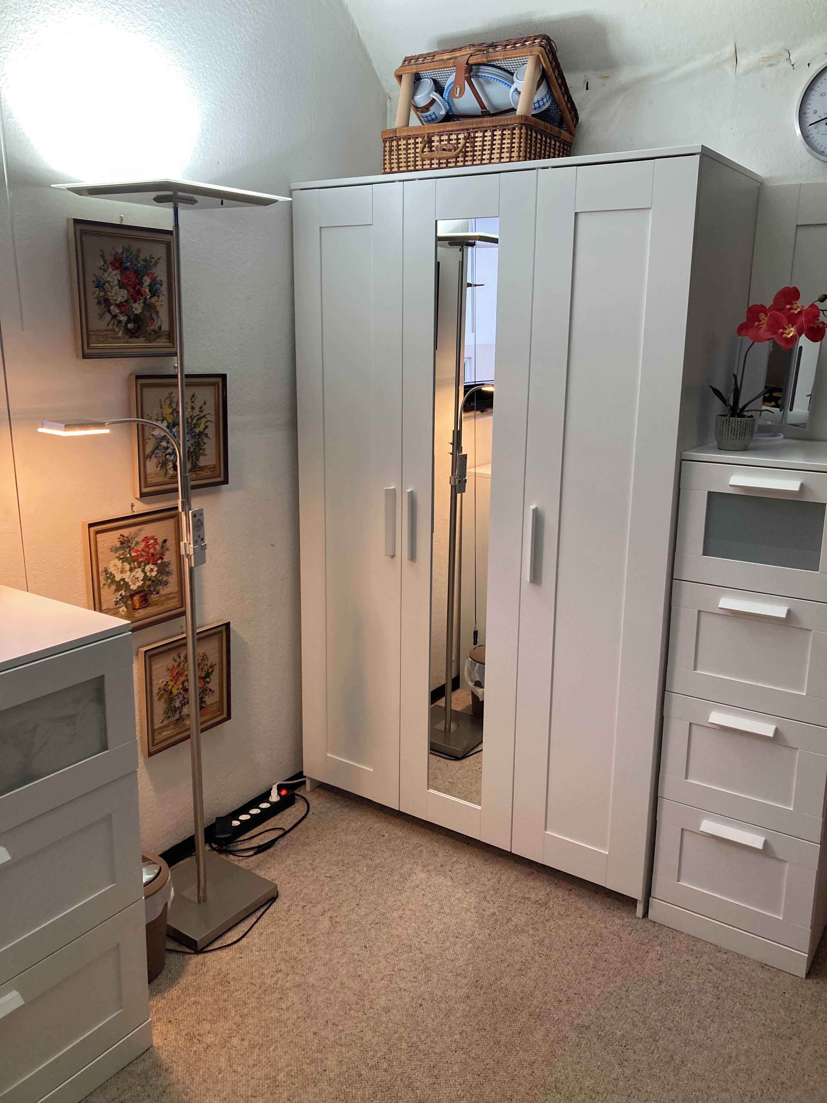 Une pièce comprenant une armoire, une lampe sur pied et une petite table sur laquelle est posée une plante en pot.