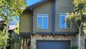 Une maison à deux étages, avec des fondations en pierre, un garage et le numéro 751 sur la façade.
