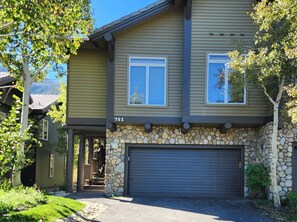 Une maison à deux étages, avec des fondations en pierre, un garage et le numéro 751 sur la façade.