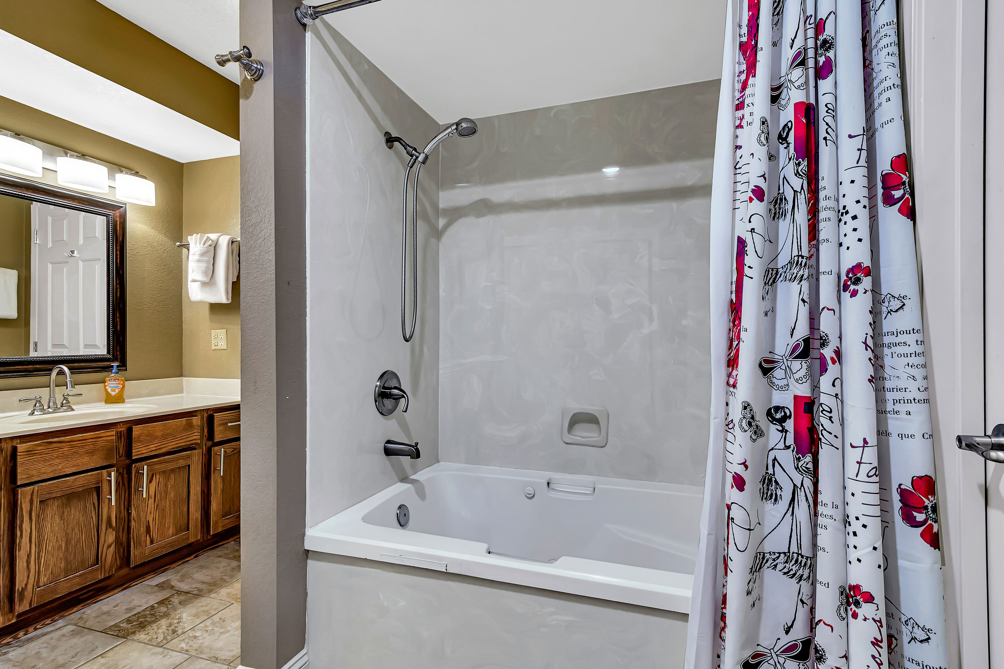 Une salle de bain comprenant une baignoire, une douche, un meuble-lavabo avec un miroir et des toilettes.