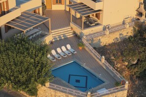 A rooftop pool area with lounge chairs and a pool with a geometric design. - Antigoni Villa, Spacious Nature Retreat with Pool (Rethymno, Crete)