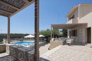A pool area with a pergola, outdoor seating, and a view of the landscape. - Antigoni Villa, Spacious Nature Retreat with Pool (Rethymno, Crete)