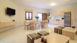 Una cucina moderna con forno a incasso, frigorifero e zona pranzo con sedie e tavolo in legno.