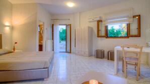 Camera d'albergo con un letto, una scrivania, una sedia e un bagno parzialmente visibile attraverso una porta aperta.