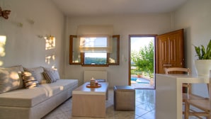 Un soggiorno moderno con divano, tavolino e vista su un giardino attraverso un'ampia finestra.