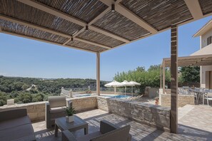 An outdoor patio with a pool, wicker furniture, and a view of the surrounding landscape. - Antigoni Villa, Spacious Nature Retreat with Pool (Rethymno, Crete)