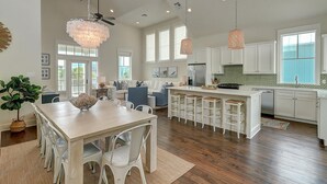A spacious kitchen with white cabinets, a central island with stools, and pendant lighting. - Cozy Beach Home in Cinnamon Shore w/ Easy Access to Resort Amenities (Port Aransas)