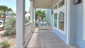 A covered porch with a view of a white picket fence and a blue building in the background. - Cozy Beach Home in Cinnamon Shore w/ Easy Access to Resort Amenities (Port Aransas)