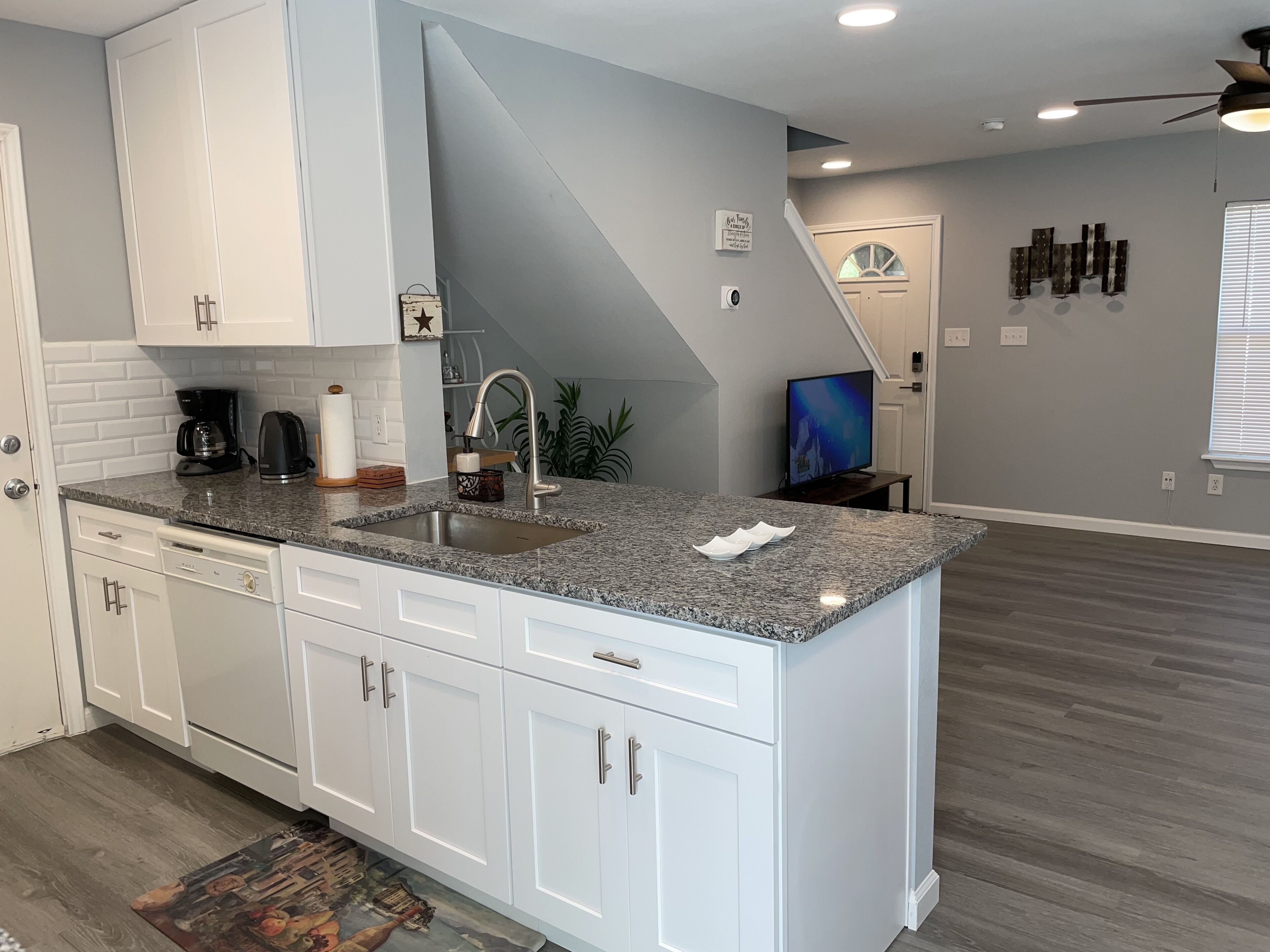 A modern kitchen with white cabinets, a granite countertop, and a built-in sink.