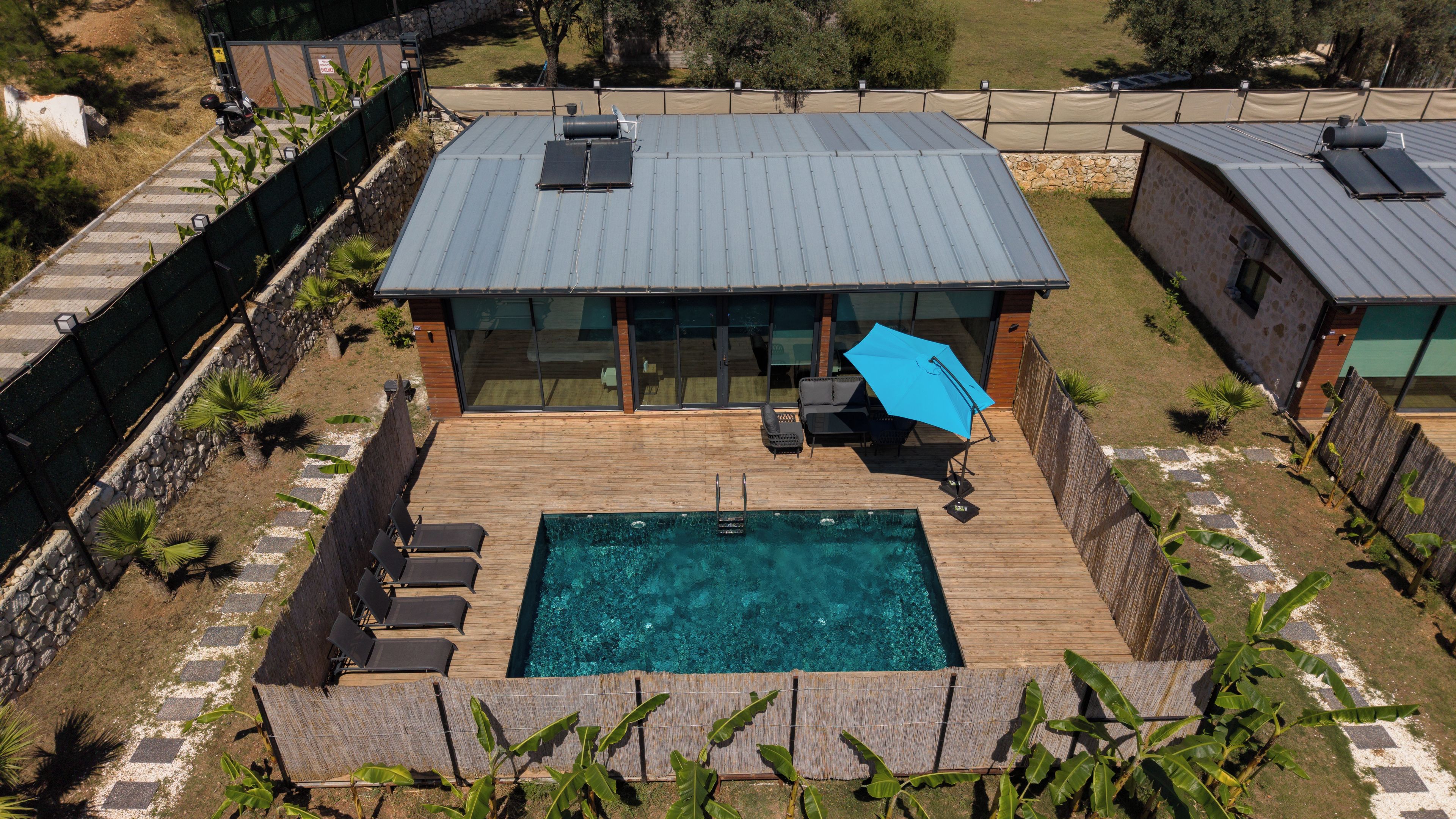 Ein modernes Haus mit Swimmingpool, überdachter Terrasse und umzäuntem Garten.