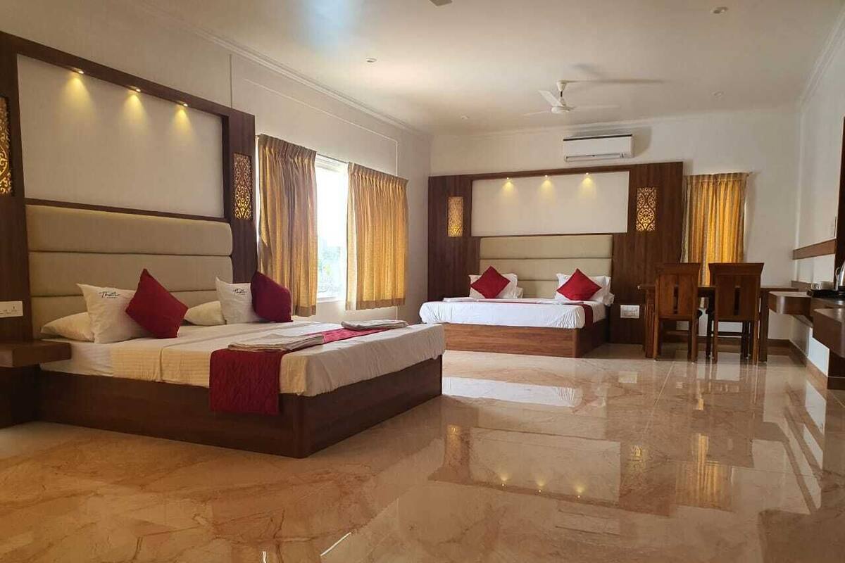 A hotel room with two beds, a sitting area, and a dining table.