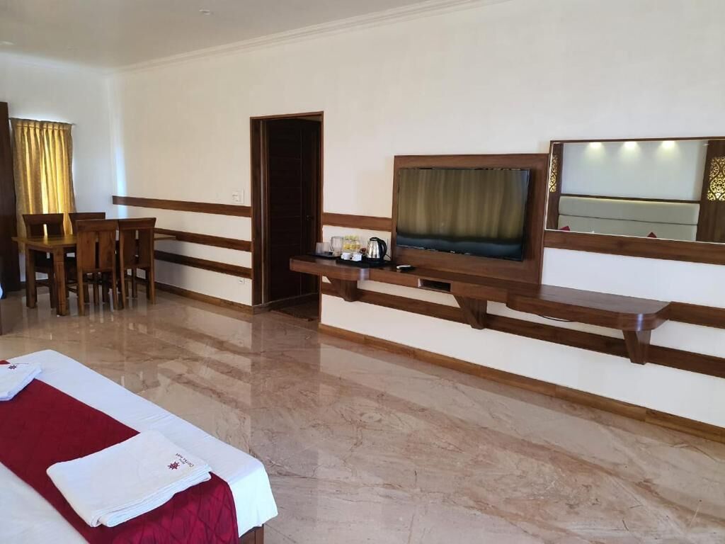 Una habitación de hotel con una cama, un escritorio, una silla, un televisor y un espejo.