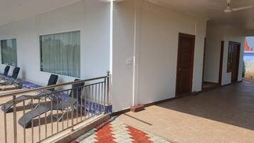A modern hotel corridor with a tiled floor, a staircase with a metal railing, and a view of the outside.