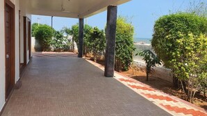 A covered corridor with tiled flooring, columns, and a view of the sea.