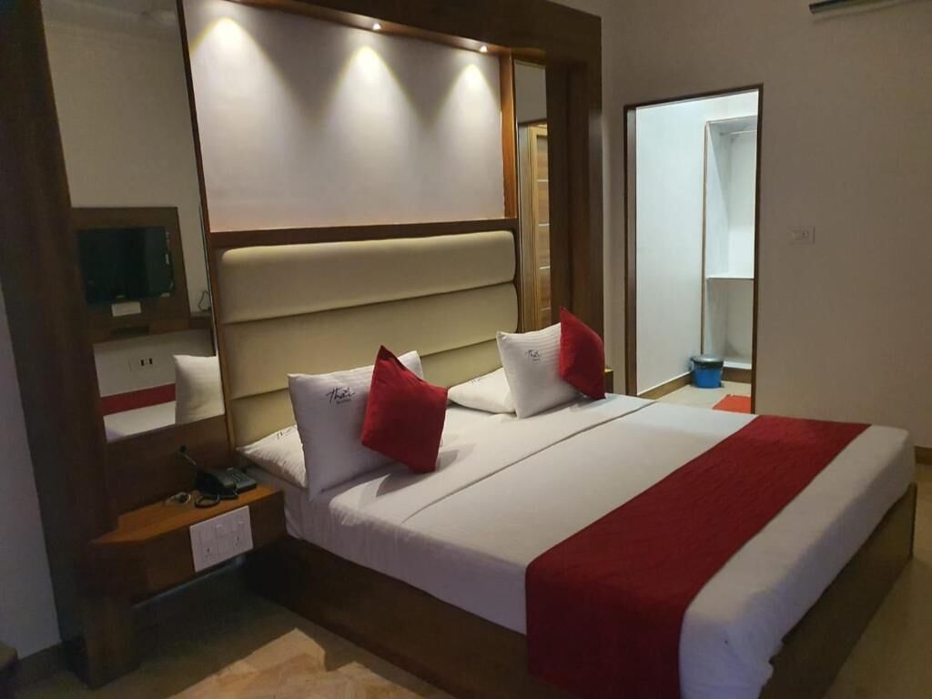 A hotel room with a large bed, a bedside table, a mirror, and a wardrobe.