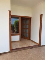 Um quarto com uma grande janela, uma porta de madeira com painéis de vidro e um piso em padrão herringbone.