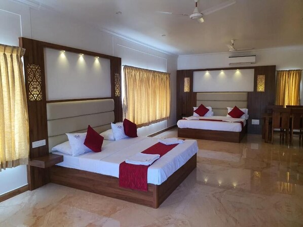 A hotel room with two beds, a ceiling fan, and a desk.