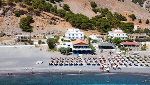 Resort costeiro com vários edifícios brancos, uma praia arenosa e mar azul cristalino.