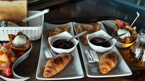 Bandeja de café da manhã com croissants, frutas, geleia e um copo de chá.