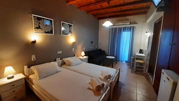 Habitación de hotel con dos camas, un escritorio, una silla, un televisor y un baño.