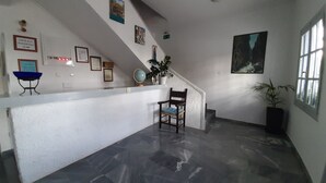 Um quarto amplo com um balcão de recepção branco, uma cadeira, um globo, quadros emoldurados e uma janela grande.