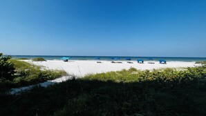 A beach with white sand and blue umbrellas.