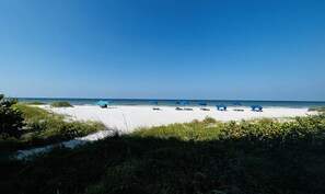 Una playa con arena blanca y sombrillas azules.
