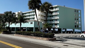 A multi-story hotel with balconies, parking, and palm trees.