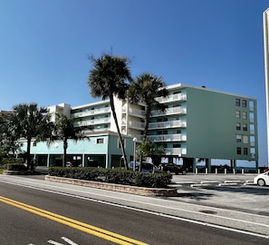 Un hotel de varios pisos con balcones, estacionamiento y palmeras.
