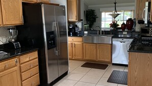 Une cuisine moderne avec des meubles en bois, des appareils électroménagers en acier inoxydable et un sol carrelé.