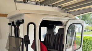 Un véhicule compact dont la porte arrière est ouverte, révélant un siège rembourré et un tissu rouge.