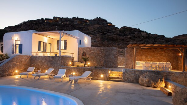 A modern villa with a swimming pool, lounge chairs, and a stone wall. - VENUS VIEW (Kalafati)