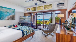 A hotel room with a bed, a desk, a chair, a ceiling fan, and a view of the ocean. - Now Renting! Kapalua Ridge 2BR/3BA Villa Ocean Views, Pools & Beach Access (Lahaina)
