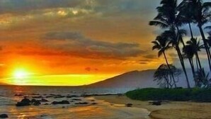 A beach with a sunset, palm trees, and a mountain in the background. - Now Renting! Kapalua Ridge 2BR/3BA Villa Ocean Views, Pools & Beach Access (Lahaina)