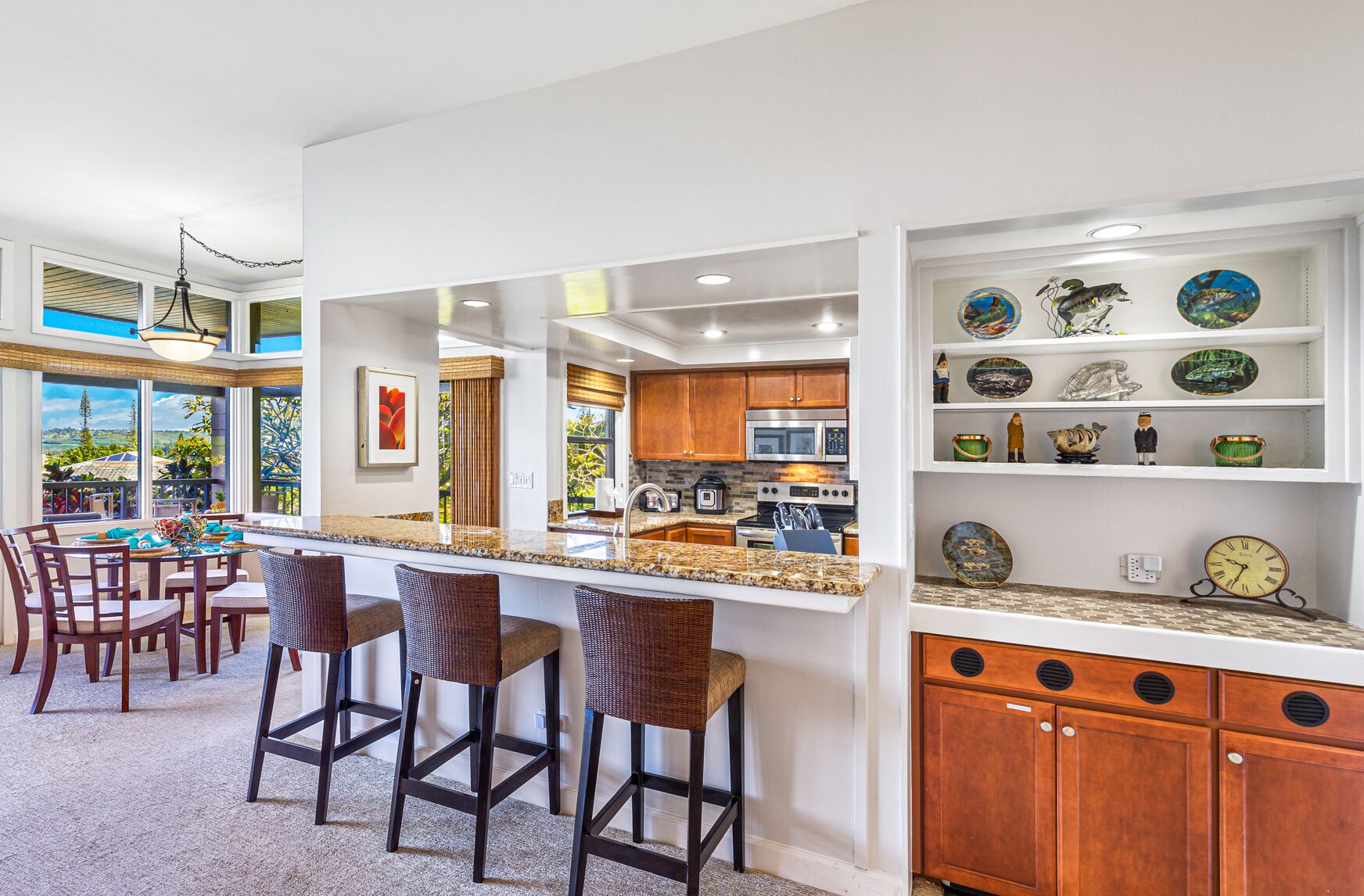 A modern kitchen with a bar area, wooden cabinets, and a view of the outdoors.