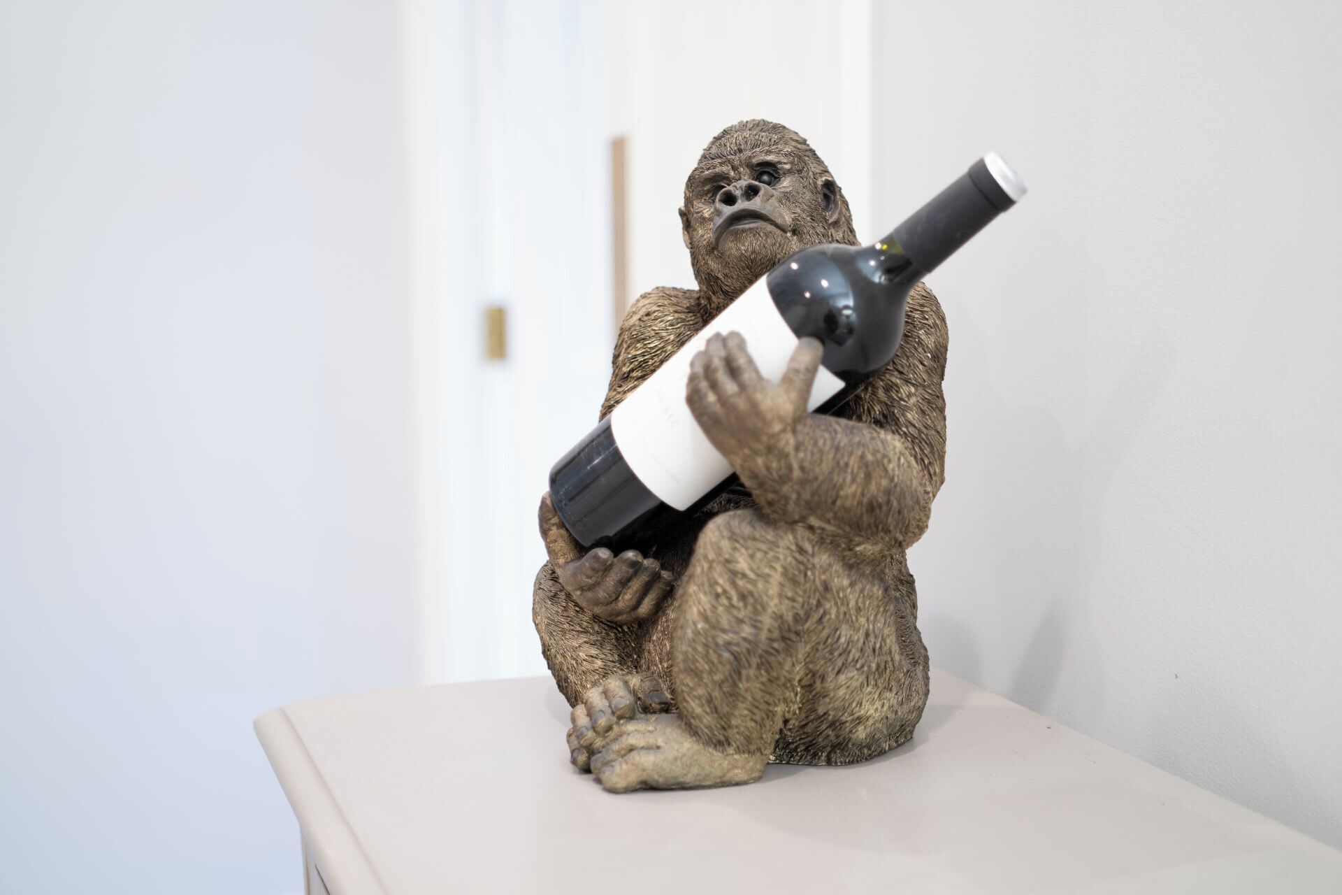 Une sculpture représentant un gorille tenant une bouteille de vin.