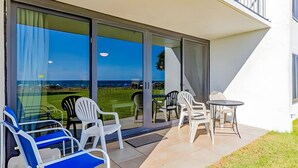 A patio with chairs and a table, a sliding glass door, and a view of the ocean. - The best location in Orange Beach - Ground floor condo - NEW to rental market (Orange Beach)