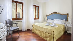 A hotel room with a bed, a chair, a dresser, and a window with curtains. - L&D Suites 51, All Saints Square (Firenze)